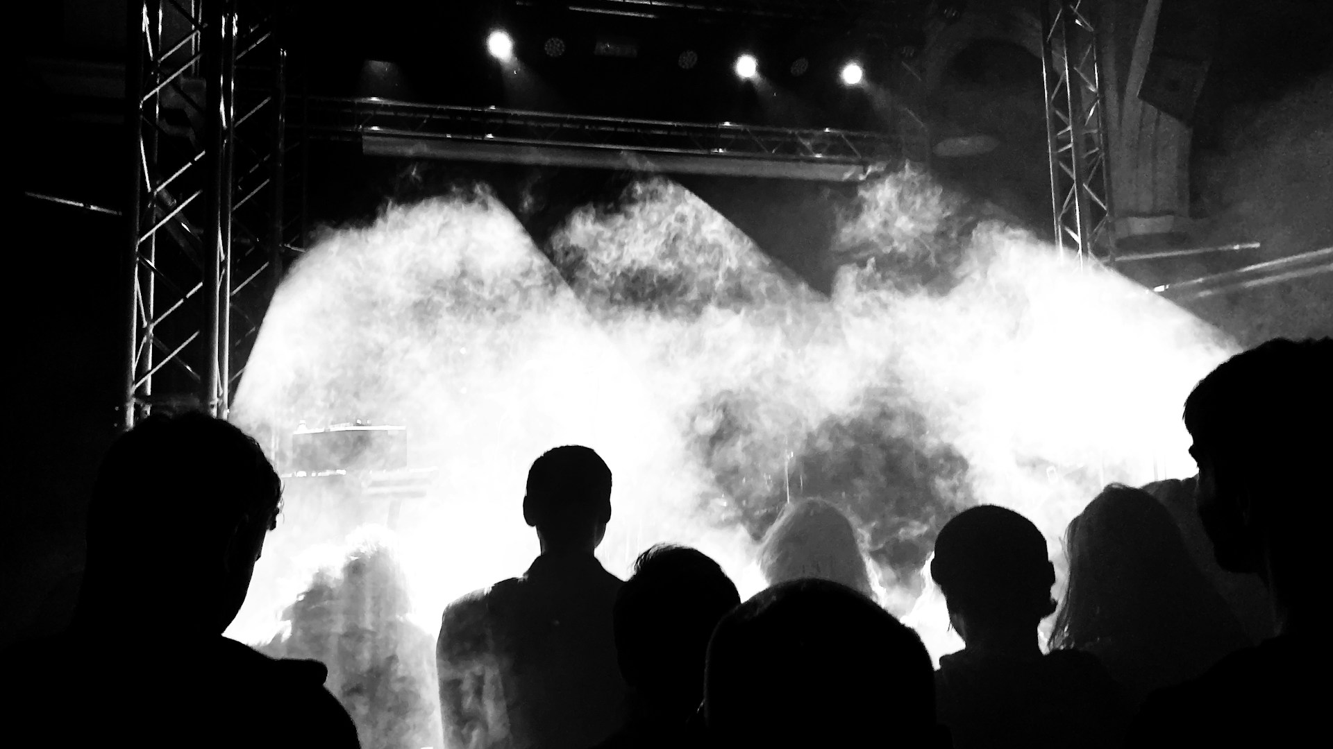 Sahne ışıkları önünde konser izleyicilerinin silüetleri